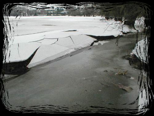 Das Eis an den Ufern des Baches bricht mit sinkendem Wasserstand ein