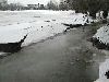 Das Eis an den Ufern des Baches bricht mit sinkendem Wasserstand ein