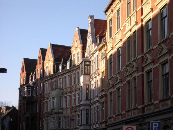 Foto: Blick in eine Strae mit mehrstckigen alten Husern mit rotbrauner Fassade und weien Fenstern