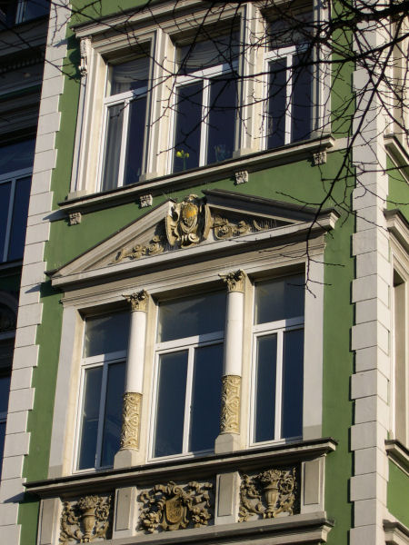 Foto: Haus mit grner Fassade, weien Fenstern und Verzierungen um die Fenster