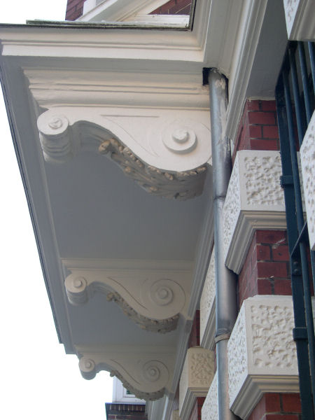 Foto: Blick von unten auf einen Vorsprung einer Hausfassade mit Verzierungen