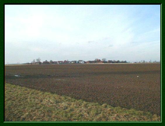 Winterliche, braune Felder, im Hintergrund die Häuser von Devese